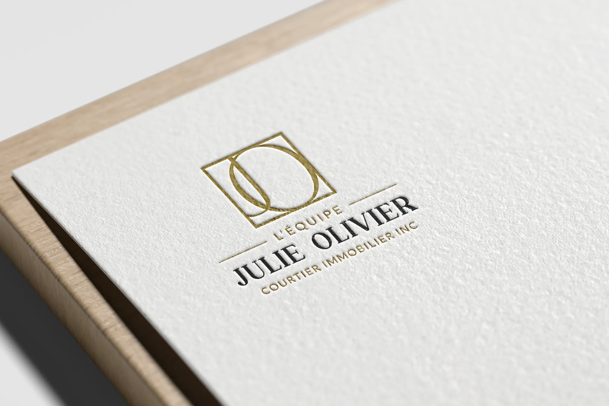 Logo de L’Équipe Julie Olivier en relief doré et noir sur papier texturé